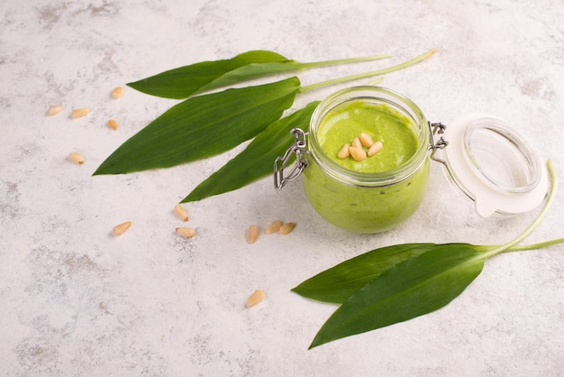 Foto gratuita pesto elaborado con piñones de ajo silvestre y queso feta en un vaso con hojas frescas sobre un texto blanco