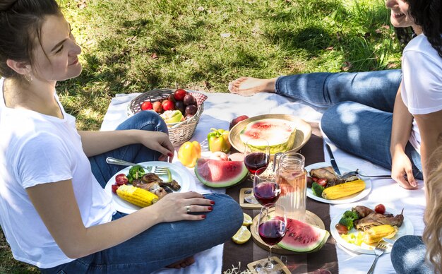 Picnic de verano con amigos en la naturaleza con comida y bebida.