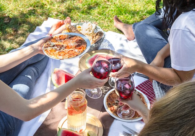 Picnic de verano con amigos en la naturaleza con comida y bebida.