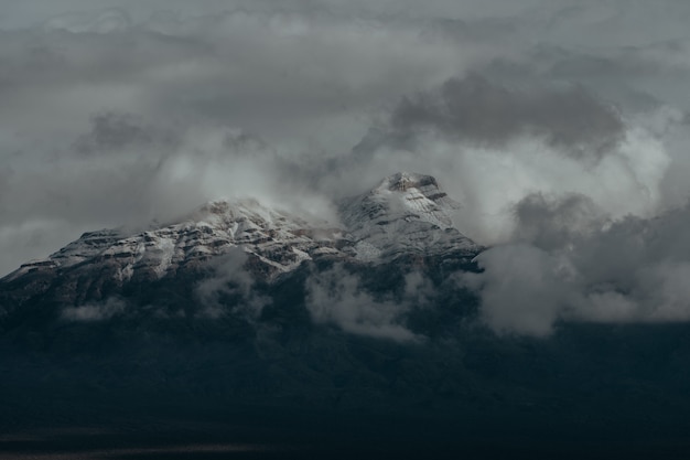 Picos nevados de las montañas cubiertas por el oscuro cielo nublado