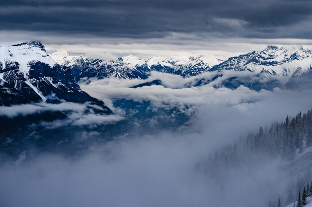 Picos nevados de montañas rocosas bajo el cielo nublado