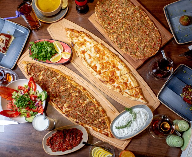 Pide y lahmajun servidos con ensalada, verduras y limón, sopa de lentejas y ayran