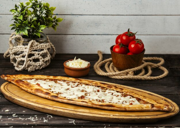 Pide tradicional turco con queso y carne rellena sobre una plancha de madera