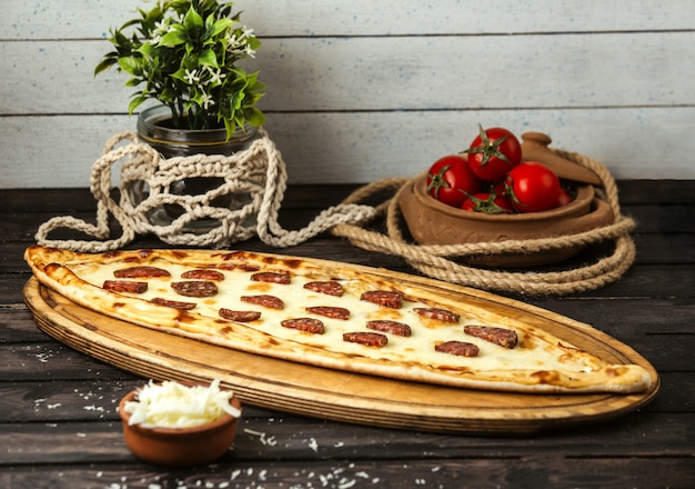 Pide tradicional turco con queso y salchichas en una tabla de madera