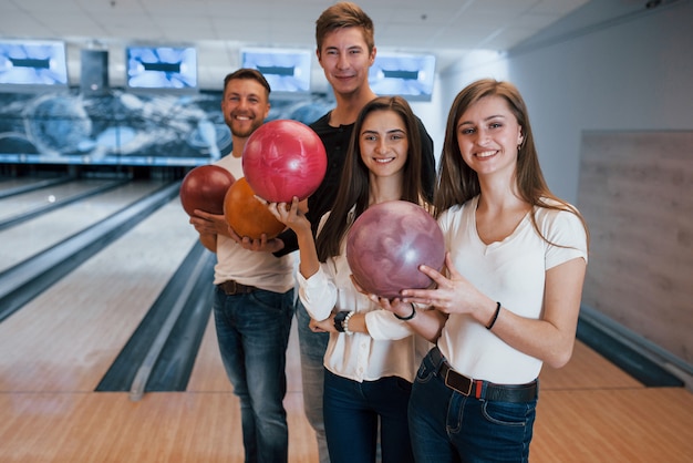 De pie contra el área de juego. Jóvenes amigos alegres se divierten en el club de bolos en sus fines de semana