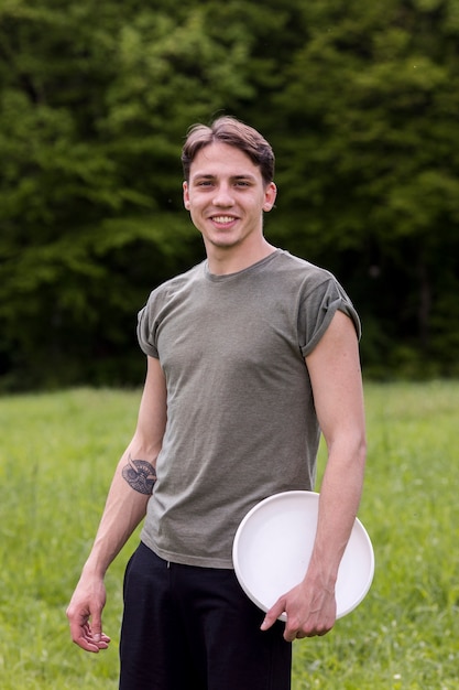Pie masculino alegre joven con frisbee en la naturaleza
