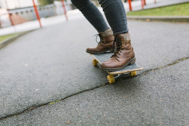 Pie de la mujer de pie en patineta en el parque