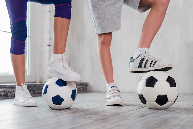 Foto gratuita pie de niña y niño sobre balón de fútbol.