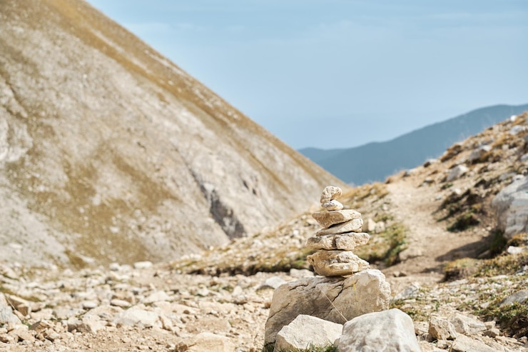 Foto gratuito piedras equilibradas zen apiladas en una pirámide en un paso en las altas montañas contra el cielo caminando