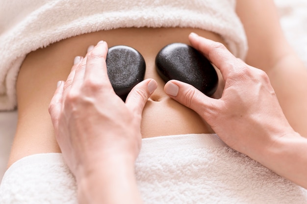 Foto gratuita piedras de spa en el abdomen del cliente