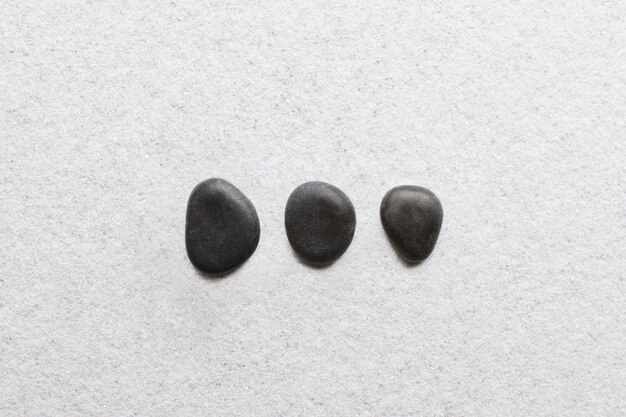 Piedras zen negras apiladas sobre fondo blanco en concepto de bienestar