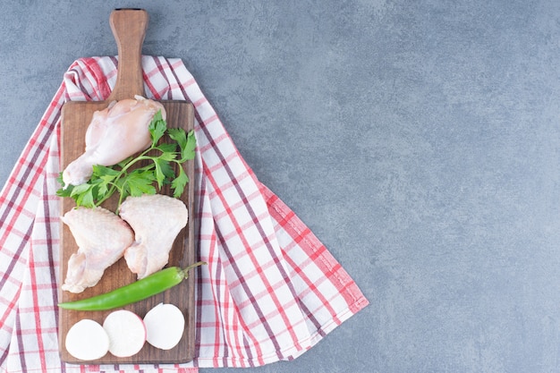 Foto gratuita pierna y alas de pollo crudo sobre tabla de madera.