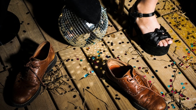 Pierna de mujer en zapato cerca de bola de discoteca y botas
