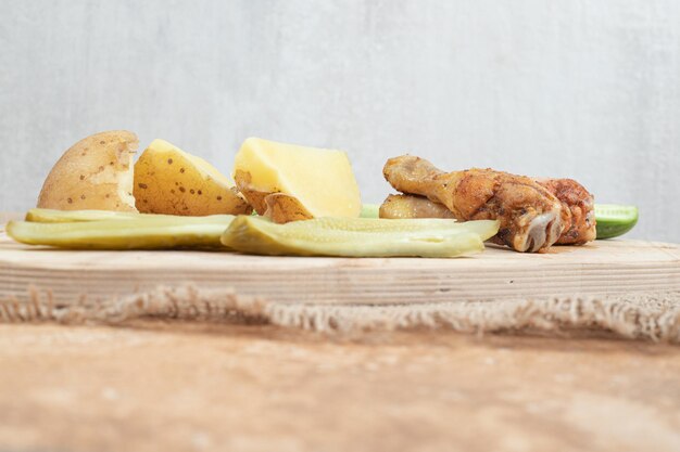 Pierna de pollo con diversas verduras sobre tabla de madera