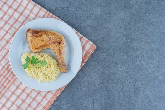 Pierna de pollo y espaguetis en un plato blanco.