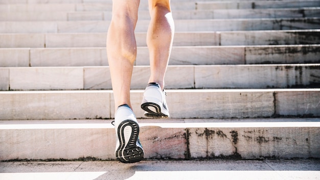 Piernas de cultivo en zapatillas corriendo arriba