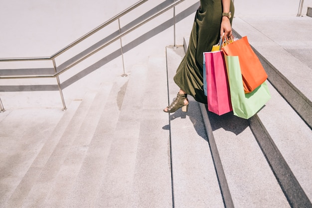 Piernas femeninas con las bolsas de las compras bajando las escaleras