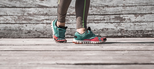 Piernas femeninas en medias y calzado deportivo sobre fondo de madera, concepto deportivo