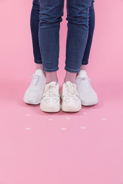 Foto gratuita piernas de hombre y mujer en jeans y zapatillas cerca de corazones decorativos