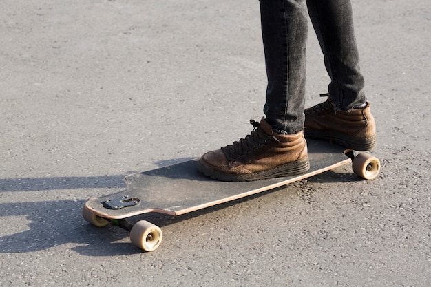 Piernas masculinas en longboard en carretera asfaltada