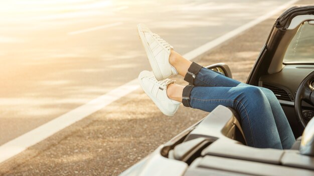 Piernas de mujer colgando por coche