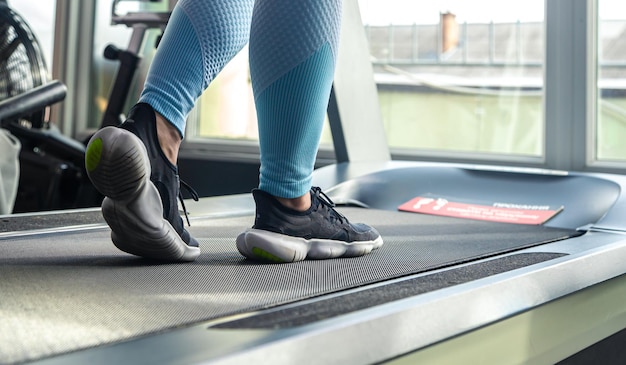 Foto gratuita las piernas de las mujeres en una cinta de correr zapatos de entrenamiento cardiovascular de primer plano