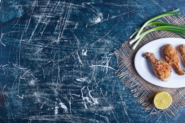 Foto gratuita piernas de pollo frito en un plato blanco.