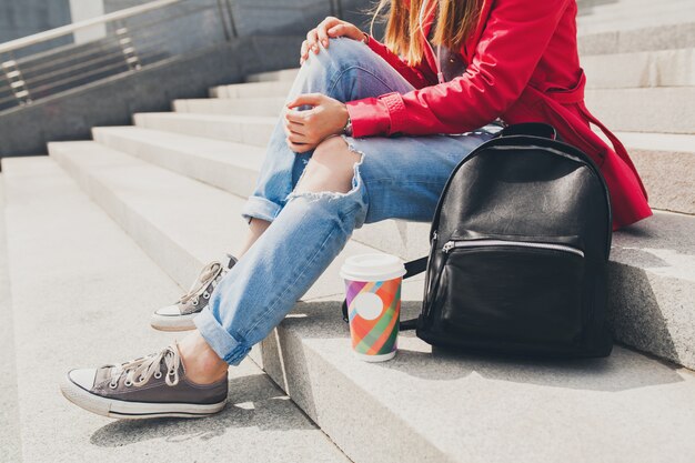 Piernas en zapatillas de deporte, tendencia de calzado de mujer joven inconformista en abrigo rosa en la calle con mochila y tendencia de estilo urbano de la gran ciudad de café