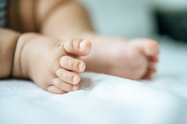 Foto gratuita pies de bebé en cama blanca.