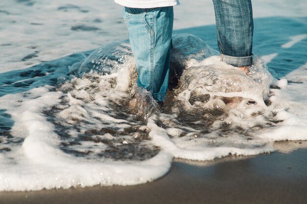 Pies de bebé y madre de pie en el mar