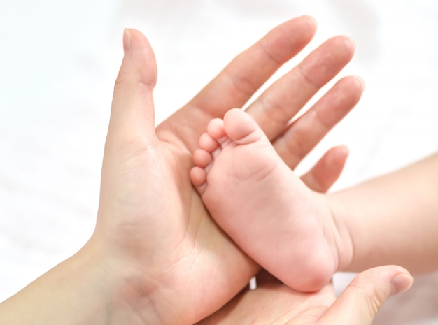 Pies del bebé en manos de la madre.