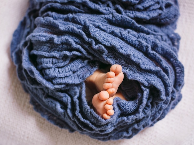 Pies de bebé recién nacido envuelto en bufanda azul