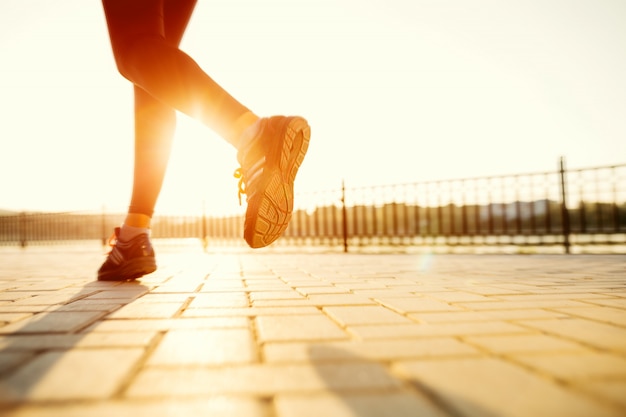 Pies de corredor corriendo en carretera closeup en zapato. Mujer fitness amanecer jog entrenamiento bienestar concepto.