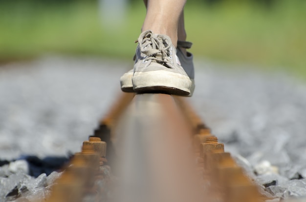 Pies femeninos en equilibrio sobre las vías del tren