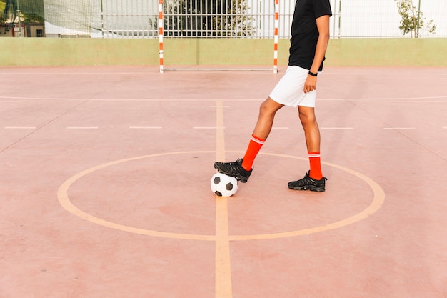 Pies de futbolista en balón de fútbol en el estadio