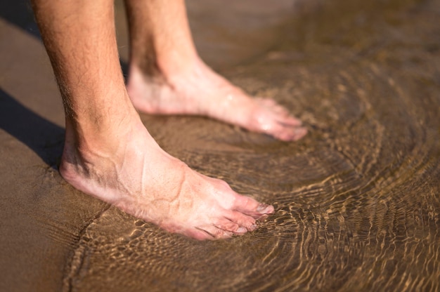 Pies del hombre de primer plano en el agua