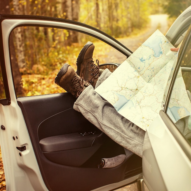 Pies de hombres con un mapa en el auto Un hombre viaja Otoño