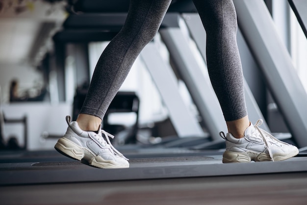 Pies de mujer deportiva de cerca corriendo en cinta en el gimnasio