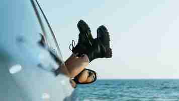 Foto gratuita pies de mujer fuera de la ventana del coche cerca del mar