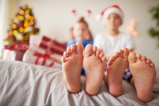 Pies de niños en la cama en Navidad