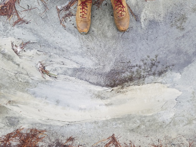 Los pies de la persona en zapatos de cuero marrón de pie sobre un suelo de hormigón desgastado