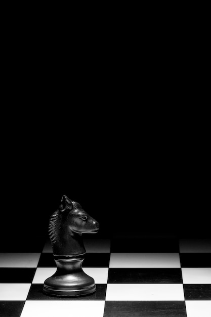 Pieza de ajedrez de caballero en el tablero contra un fondo negro