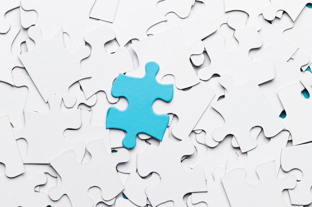 Pieza de puzzle azul sobre piezas de puzzle blanco