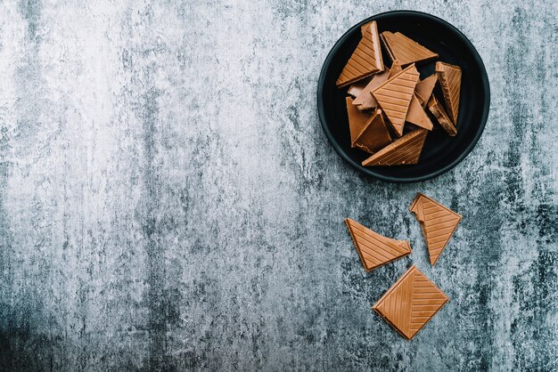 Piezas de chocolate en un tazón sobre el fondo degradado