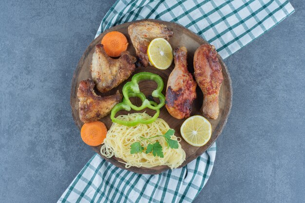 Piezas de pollo a la plancha y espaguetis sobre pieza de madera.