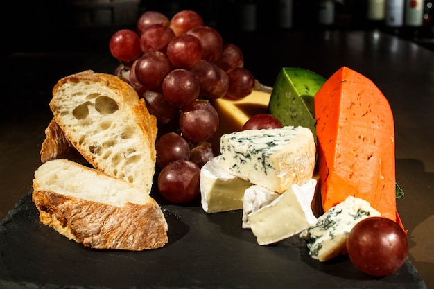 Piezas de queso y pan en plato negro