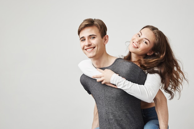 Piggyback novia feliz y su novio sonriendo. Par se ve feliz