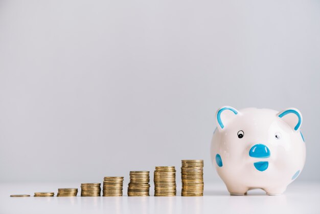 Piggybank y aumento de monedas apiladas en el escritorio reflexivo