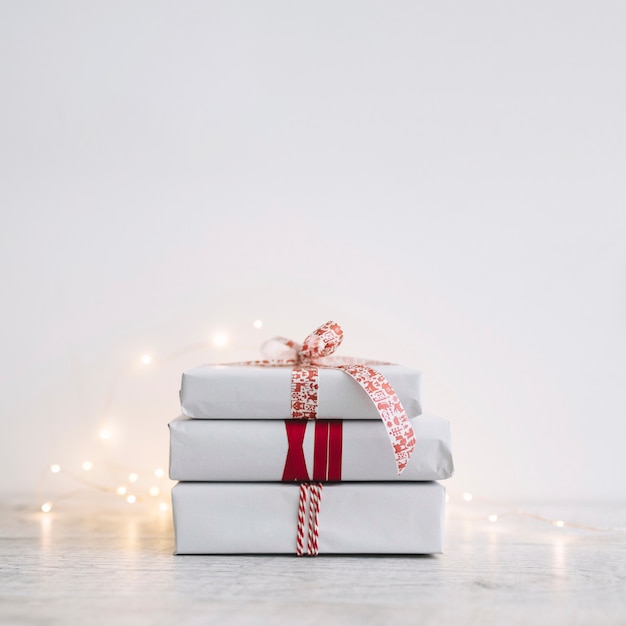 Foto gratuita pila de cajas de regalo blancas con guirnalda en mesa
