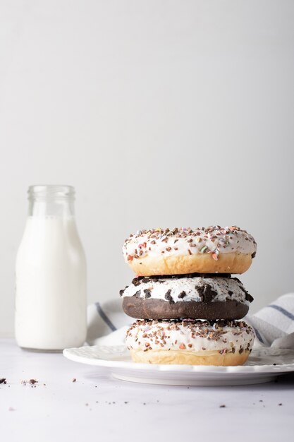 Pila de donas glaseadas con chispas y botella de leche